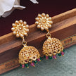 gold plated jhumki earrings with pink and green pearl drops showcased on a wooden box.