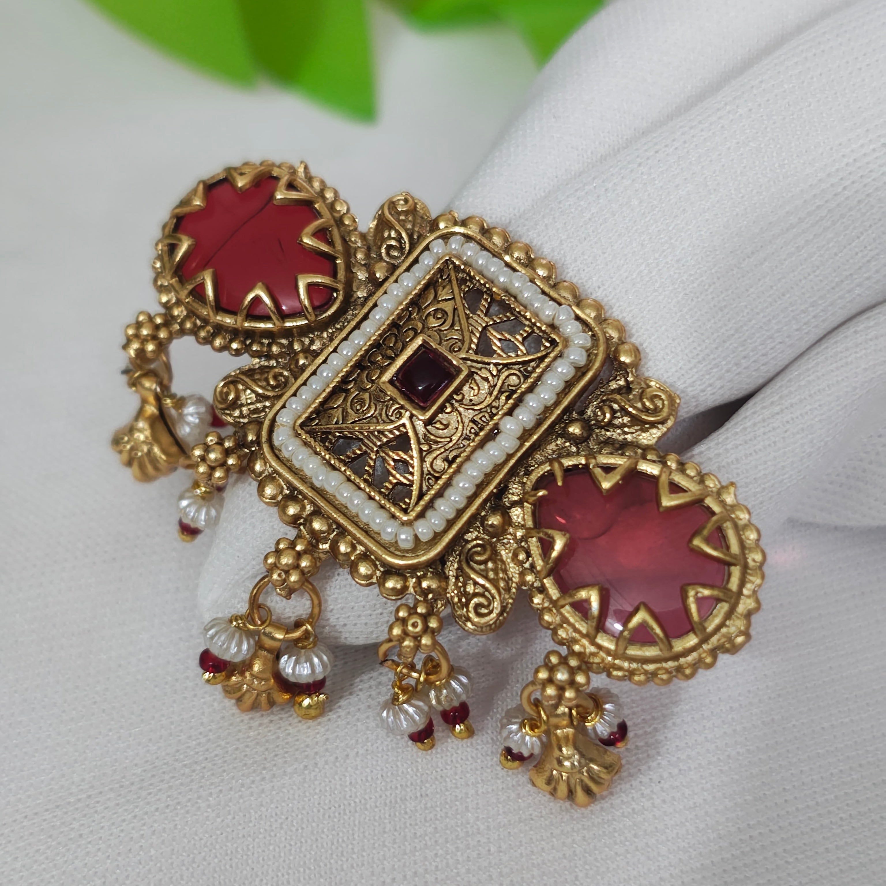 Antique gold kundan ring design featuring red stones and pearl drops, showcasing intricate craftsmanship.