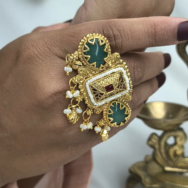 Rajasi Antique Gold Kundan Ring featuring green stones and pearl drops on a hand.