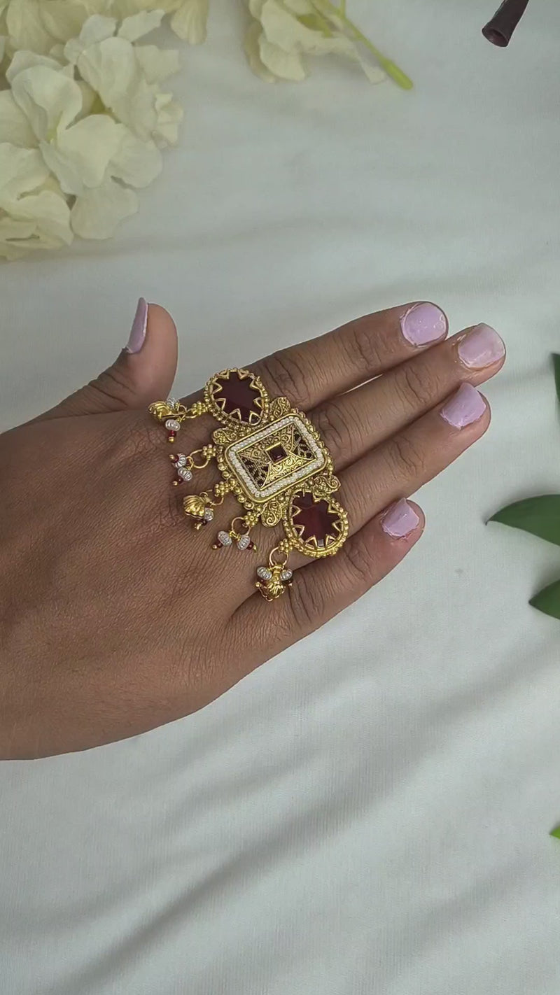 Antique gold kundan ring design featuring red stones and pearl drops, showcasing intricate craftsmanship.